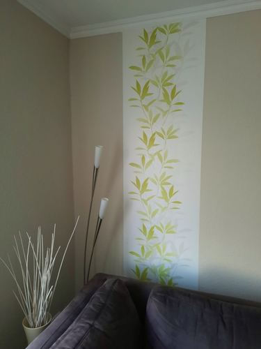 Wohnzimmer mit heller Akzentwand und dezentem Blattmuster